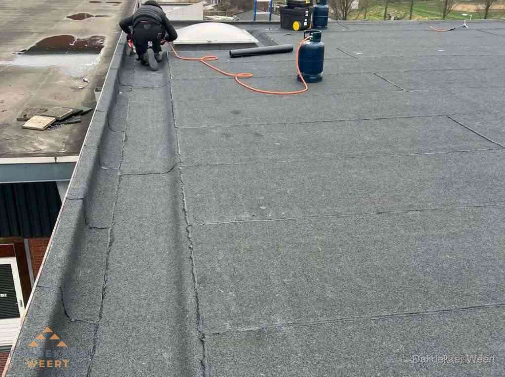 Dakdekker repareert bitumen dakbedekking op groot plat dak in Weert